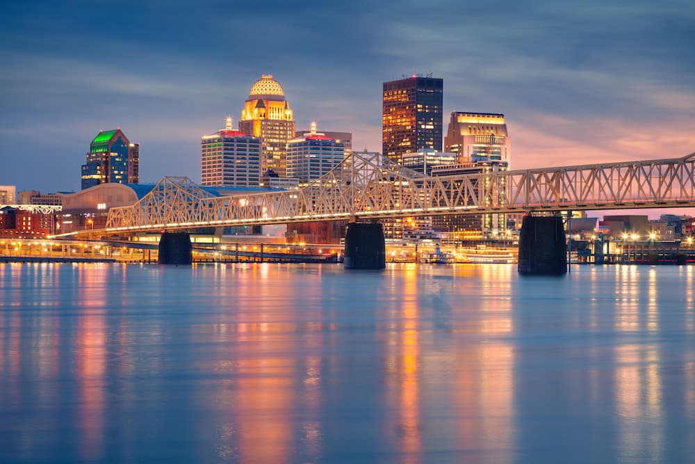 Dusk view of the Louisville, Kentucky skyline and the illuminated Big Four Bridge over the Ohio River.